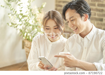 A couple looking at a smartphone 87190722