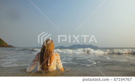 Woman in a White Tunic on the Beach, near the Sea. Blonde in Sun 87194767