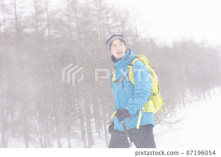 Young man walking in a snowy mountain 87196054