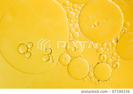 Golden yellow abstract oil bubbles or face serum background. Oil and water bubbles macro photography. 87198336