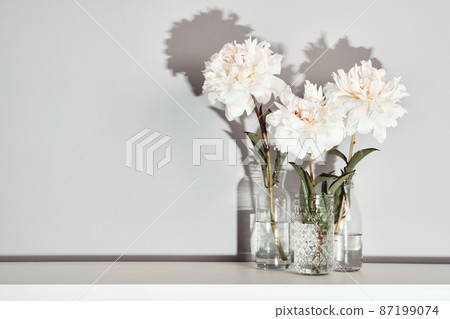 Elegant white peonies flowers arrangement on table wall background, trendy shadows 87199074