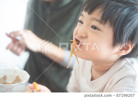 Profile of a 4-year-old boy eating noodles for lunch in his living room 87199207