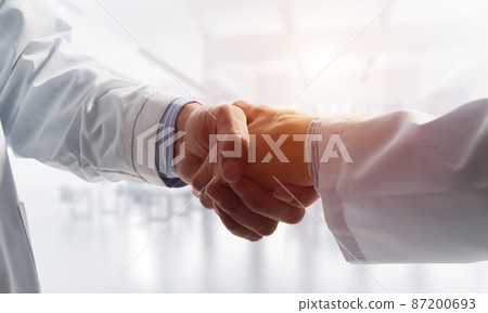 Close-up of the handshake between the two medics. Against the backdrop of the cityscape 87200693