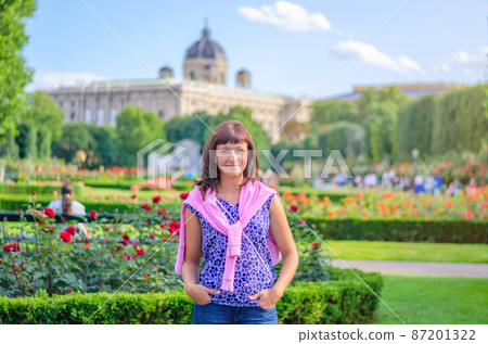 Young beautiful caucasian girl with flowered shirt looking at camera, posing and smile in Volksgarten garden park 87201322