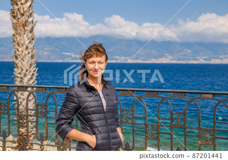Young beautiful woman traveler looking at camera, smile, posing and keep hands in pockets Young beautiful woman traveler looking at camera, smile, posing and keep hands in pockets 87201441