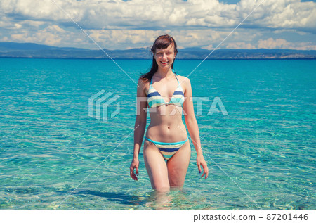 Young beautiful girl in bikini stay in turquoise water of Toroneos kolpos gulf 87201446