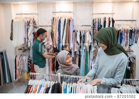 asian muslim family buying new clothes together in clothing store 87203302