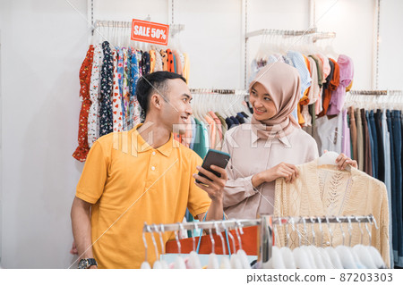 couple looking at smartphone while shopping together at the shop 87203303