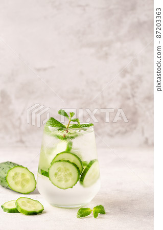 Fresh infused cucumber water on a light background Fresh infused cucumber water on a light background 87203363