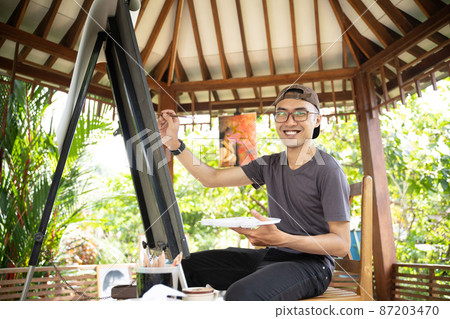 male painter painting on canvas in his workshop male painter painting on canvas in his workshop 87203470