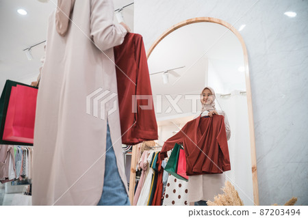 muslim woman trying dress in mirror in fitting room 87203494