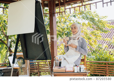 muslim Female artist painting on canvas drink tea muslim Female artist painting on canvas drink tea 87203580