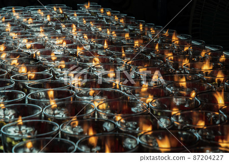 Detail of Many red votive candles light with shallow depth of field inside Chinese temple. Detail of Many red votive candles light with shallow depth of field inside Chinese temple. 87204227
