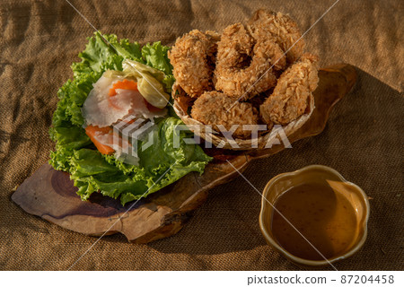 Deep-fried shrimp cakes (Tod Mun Goong) and vegetable with chili sauce on wooden background. Deep-fried shrimp cakes (Tod Mun Goong) and vegetable with chili sauce on wooden background. 87204458