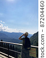 Man with a hat looks binoculars into the distance. Mountain landscape. Mobile photo 87204460