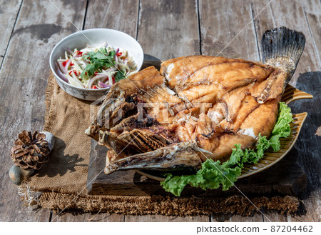 Deep fried Snapper with fish sauce on vintage wooden. 87204462