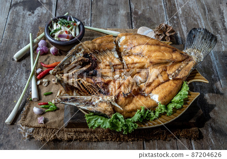 Deep fried Snapper with fish sauce on vintage wooden. 87204626
