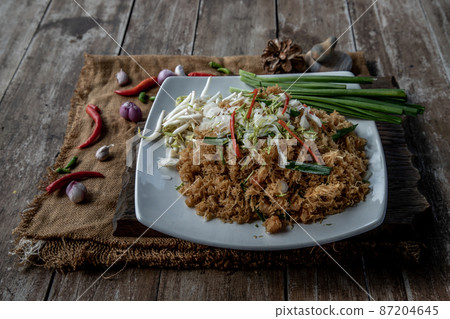 Asian eating food, Mee Grob is an sweet and sour crispy noodles, made from Thai rice noodle with sweet and sour sauce on white plate, Sweet & Sour Crispy Rice Noodles. 87204645