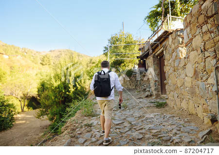 Tourist walks among ancient houses in Phicardou (Fikardou) village, Cyprus. 87204717