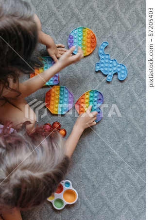 View from above to children playing with pop it toys View from above to children playing with pop it toys 87205403