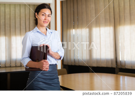 Confident Asian businesswoman standing with briefcase in meeting room Confident Asian businesswoman standing with briefcase in meeting room 87205839