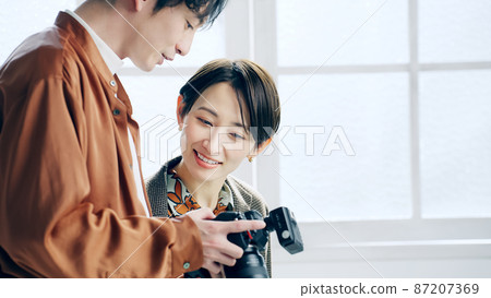 A cameraman who shows the LCD of the camera to the model 87207369