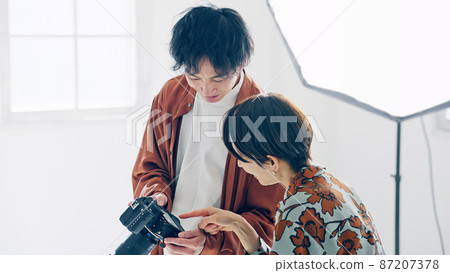 向模特展示相機液晶顯示屏的攝影師 87207378