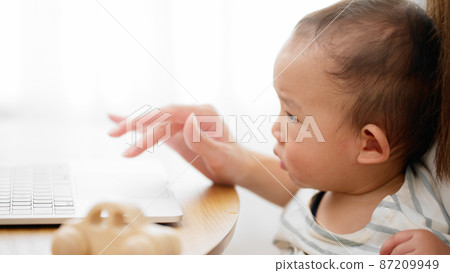 Mother showing her laptop to her baby Mother showing her laptop to her baby 87209949
