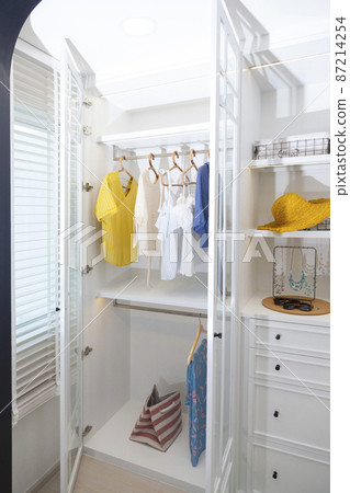 A Large White Built-in Wardrobe Stocked With Clothing, Shoes and Accessories. Walk-in closet, Dressing Room. 87214254