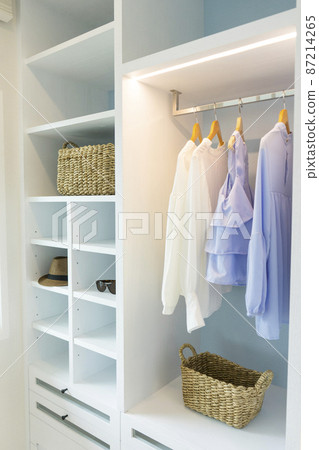 A Large White Built-in Wardrobe Stocked With Clothing, Shoes and Accessories. Walk-in closet, Dressing Room. 87214265