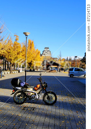 Overlooking Himeji Castle against the backdrop of Ginkgo trees and motorcycles under clear skies 87214713