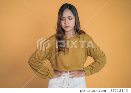 Young asian woman in pain with both hands holding stomach 87218143