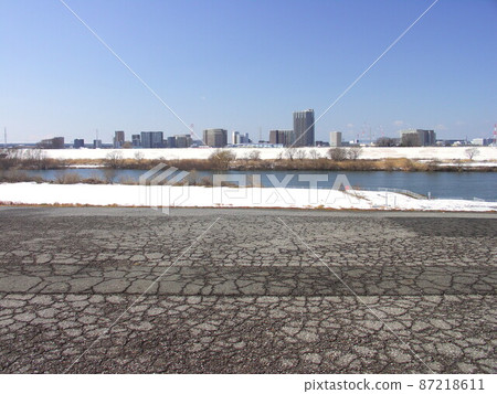 The riverbed and the opposite bank of the remaining snow seen from the dedicated road on the bank of the cracked Edo River The riverbed and the opposite bank of the remaining snow seen from the dedicated road on the bank of the cracked Edo River 87218611