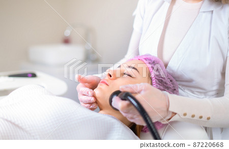 Young woman receiving treatment in cosmetology clinic. Cosmetology skin care. Aesthetic facial treatment Concept. 87220668
