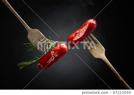 Grilled sausages with rosemary on a forks. 87221059