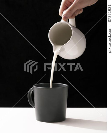 front view hand pouring milk into mug 87221921