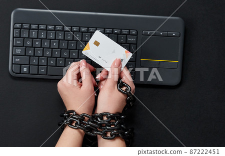 Woman with metal chain holding credit card over keyboard, online shopping addiction concept 87222451