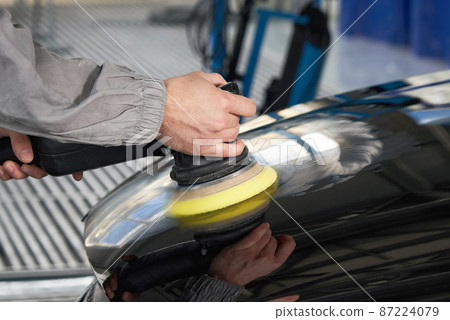 hands holding polisher to polish car in auto workshop 87224079