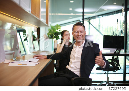 portrait of cheerful young businessman give thumb up to camera. 87227695