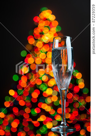 champagne glass against christmas tree bokeh 87229359