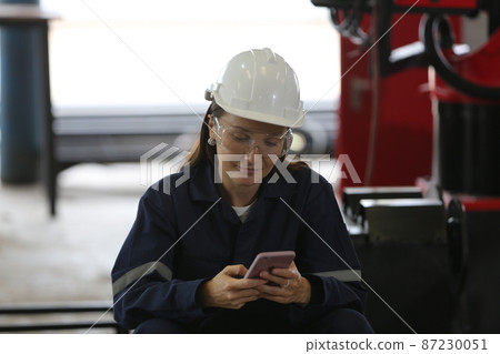 Female industrial worker working with manufacturing equipment in a factory 87230051
