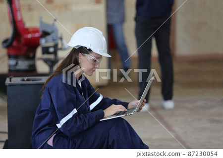 Female industrial worker working with manufacturing equipment in a factory 87230054