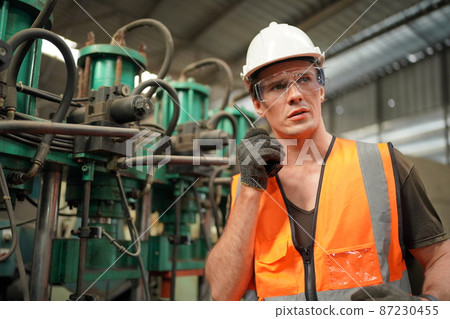 Professional engineer metalworker operating CNC milling machine center in manufacturing workshop 87230455