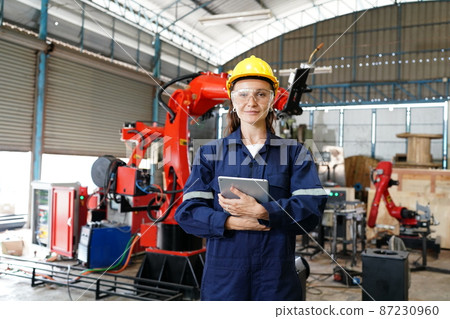 Female industrial worker working with manufacturing equipment in a factory 87230960