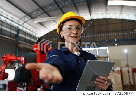 Female industrial worker working with manufacturing equipment in a factory Female industrial worker working with manufacturing equipment in a factory 87230977