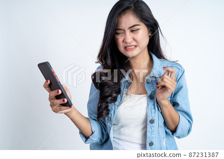asian woman shocked while using mobile phone 87231387