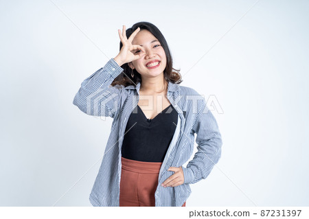 Young woman showing oke gesture with eye looks imitating binoculars Young woman showing oke gesture with eye looks imitating binoculars 87231397