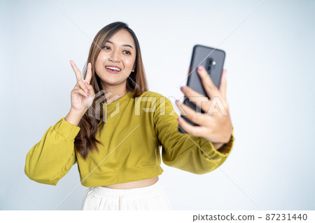 young woman take a selfie with peace hands gesture young woman take a selfie with peace hands gesture 87231440