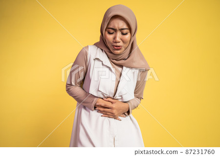 muslim woman in pain with both hands holding stomach when stomachache muslim woman in pain with both hands holding stomach when stomachache 87231760