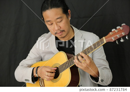 Portrait of men musician playing guitar in studio. Portrait of men musician playing guitar in studio. 87231784